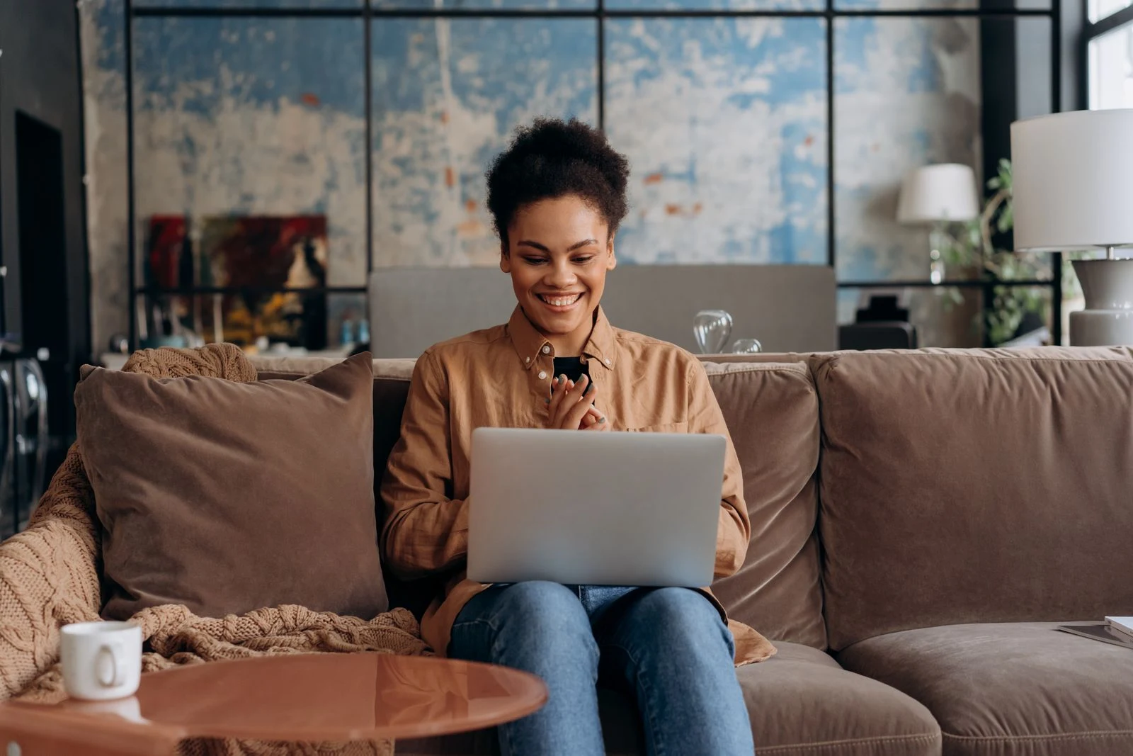 Mulher sorrindo enquanto usa um notebook em casa — imagem ilustrativa